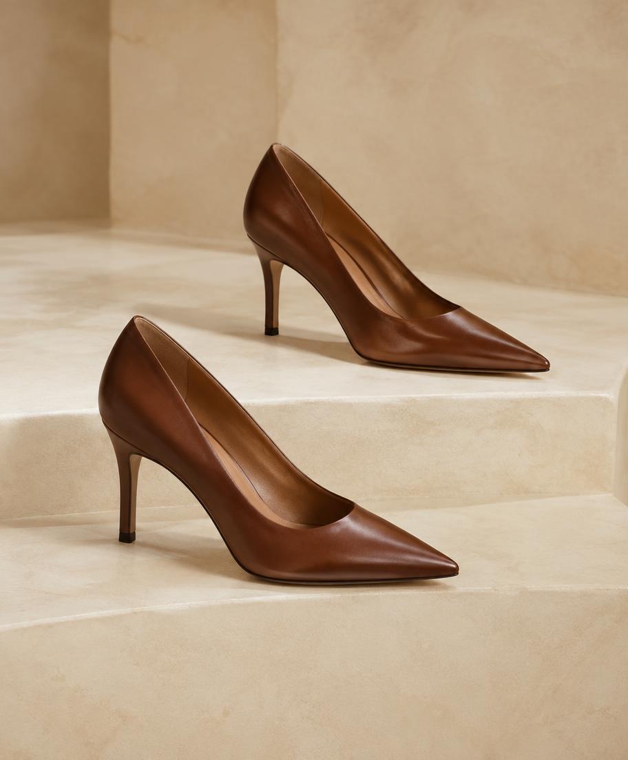 Pair of cognac leather pointed heels on pale stone steps
